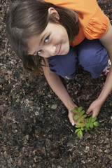 Elevated portrait view of a smiling girl planting black locust tree