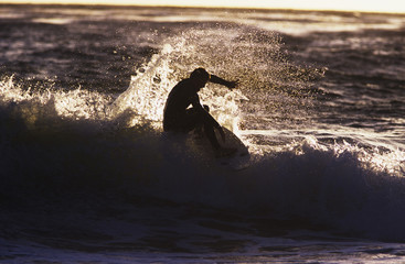 Side view of a silhouette man surfing wave