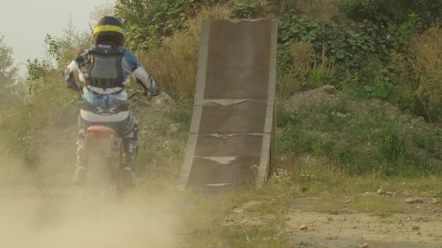 SLOW MOTION: Extreme pro motocross biker riding motorbike and jumping huge jump