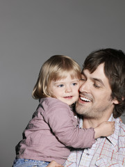 Happy loving father carrying daughter isolated on grey background