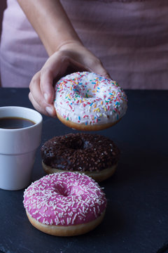 hand holding donut and coffee on a black background