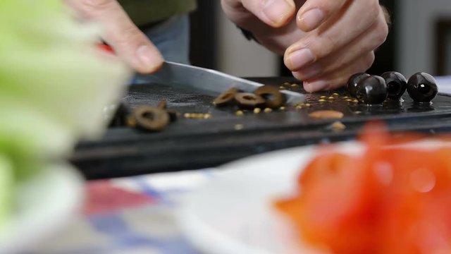 man cutting olives for a salad