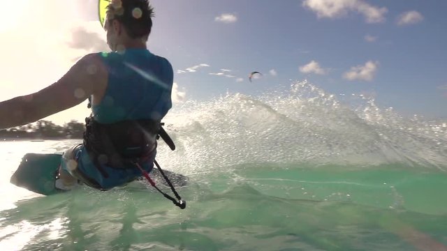 SLOW MOTION: Young surfer man has fun kitesurfing in island lagoon at sunset