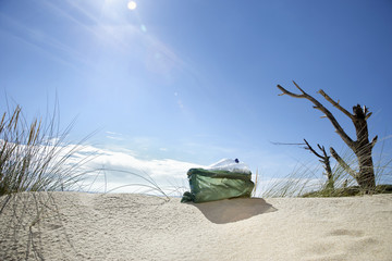 Plastic bag filled with empty bottles on a sunny beach