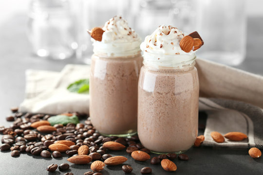 Tasty milk shake cocktails with coffee beans and almond nuts on table