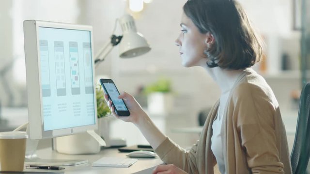 Beautiful Burnette Compares Her Smartphone Screen with Her Desktop Computer Screen. All Happening in Modern and Light Office. Shot on RED Cinema Camera in 4K (UHD).