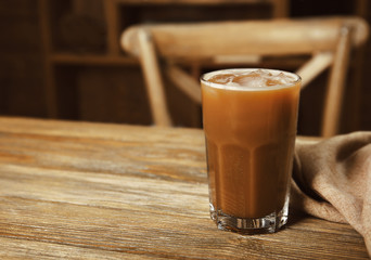 Glass of cold coffee with napkin on table