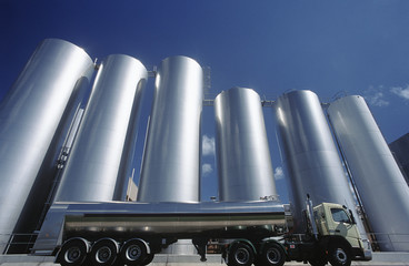 Milk transport truck parked alongside storage tanks
