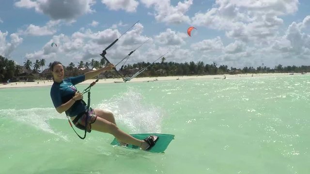 SLOW MOTION: Smiling young surfer woman kiteboarding in beautiful blue lagoon