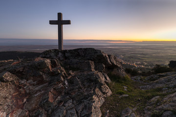 Dawn with cross in the foreground next to Sierra de Fuentes. Spain. - obrazy, fototapety, plakaty