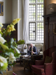 Mature businessman sitting on antique furniture and using cellphone