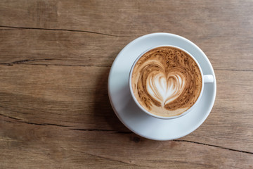 hot cappucino with latte art in heart shape on a wooden background