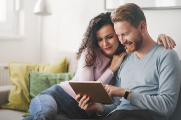 Happy couple surfing on tablet at home