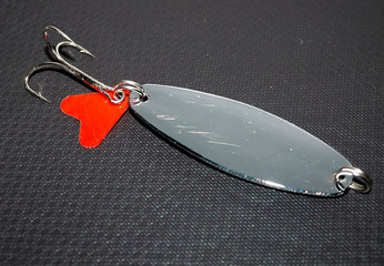 metal lure for catching fish on a black background © kvdkz