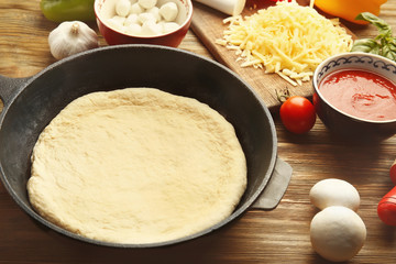 Unbaked pizza in pan on wooden table