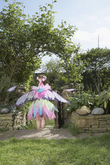 Rear view of a young girl in fairy costume standing in the garden