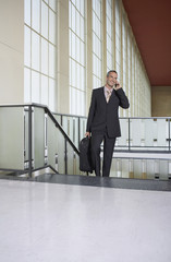 Businessman using mobile phone on escalator in the airport