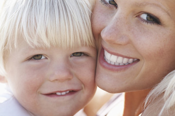 Closeup portrait of cute little boy and mother cheek to cheek