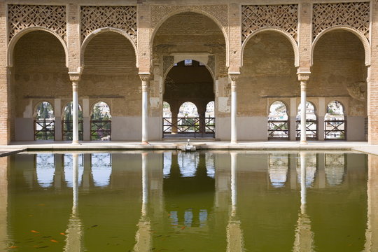 Portico of the Torre de las Damas reflected in tranquil pool, Jardines del Partal, Alhambra, Granada, Andalucia (Andalusia), Spain