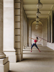 Full length of a female athlete throwing javelin in portico