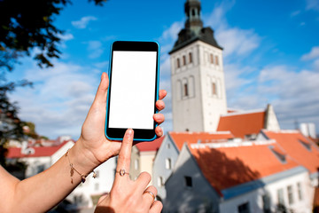 Naklejka premium Phone with white screen on the old town background in Tallinn, Estonia