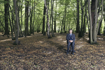 Obraz premium Full length portrait of businessman sitting in middle of forest