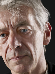 Closeup of sad senior man looking away on black background