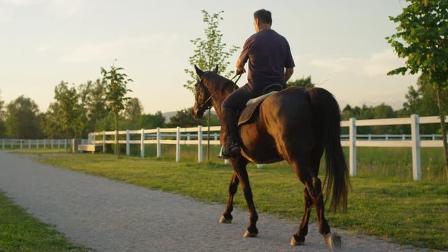 CLOSE UP: Senior horseman horseback riding an enjoying time at sunrise