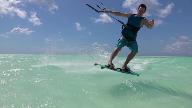 SLOW MOTION: Happy kite surfer kiting and jumping, splashing water into camera