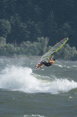 Obraz premium Side view of a man jumping whilst windsurfing