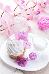 White cake with cream protein with the decor of pink flowers on a wooden table