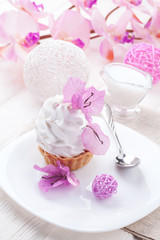 White cake with cream protein with the decor of pink flowers on a wooden table