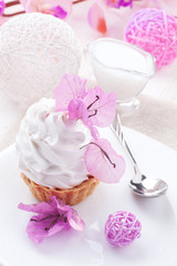 White cake with cream protein with the decor of pink flowers on a wooden table