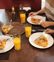 Friends sitting in cafe with tasty pizza and juice, close up view
