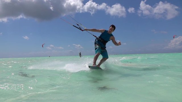 SLOW MOTION: Kite surfer kitesurfing and jumping, splashing seawater into camera
