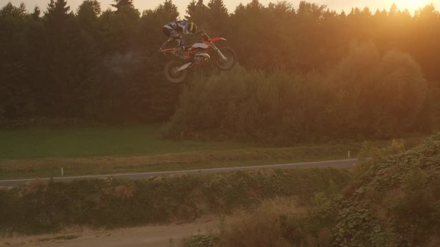 AERIAL SLOW MOTION: Extreme pro biker riding motocross jumping superman trick