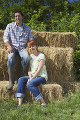 Naklejka na ściany i meble Portrait of a couple sitting on hay bales in countryside