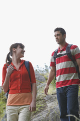 Low angle view of a young couple walking with backpacks in countryside