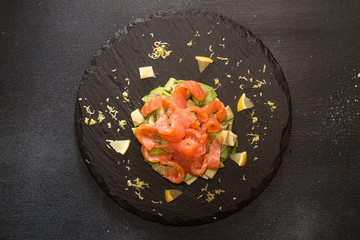 Tartare of salmon and avocado. Fresh salad on stone slate
