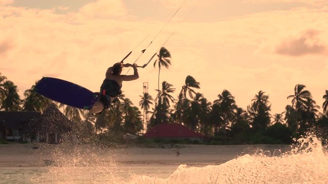 SLOW MOTION CLOSEUP: Extreme kiter girl kiteboard jumping rally at golden sunset