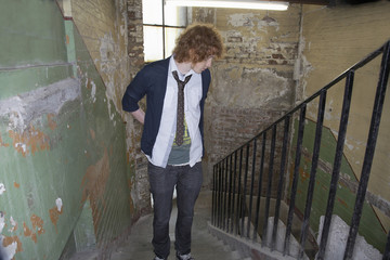 Young man standing on steps of old weathered building