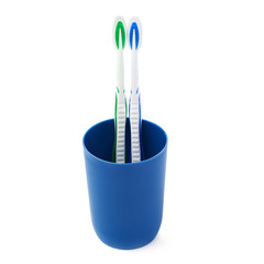 Pair of toothbrushes in blue plastic cup isolated over white background
