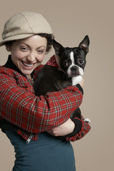 Portrait of smiling young woman holding French Bulldog on colored background
