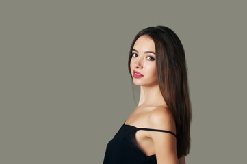 young woman standing sideways looking at the camera. Isolated gray background