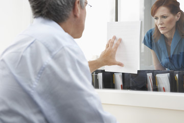 Rear view of a male executive showing woman document in office