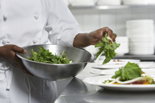 Closeup midsection of a chef preparing salad in the kitchen
