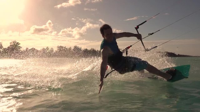SLOW MOTION: Happy surfer hand drag kiteboarding in tropical lagoon at sunset