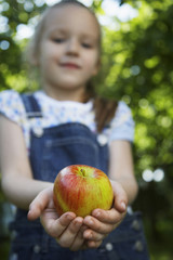 Blurred young girl holding out a fresh apple