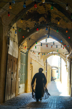 Mullah hurrying down typical vaulted alleyway, Yazd, Iran