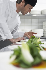 Side view of a male chef preparing salad in kitchen